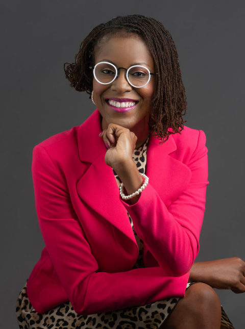 Woman smiling for her business headshot in a bright red fuchsia blazer with a cheetah print dress underneath, while also wearing white round glasses, and matching pearl bracelets and earrings, Moreland Photography, Atlanta headshot photography, business headshot, professional headshot, atlanta photographer, business headshot portrait, blazer, red blazer, fuchsia blazer, pearls, pearl jewelry, jewelry, white glasses, round glasses